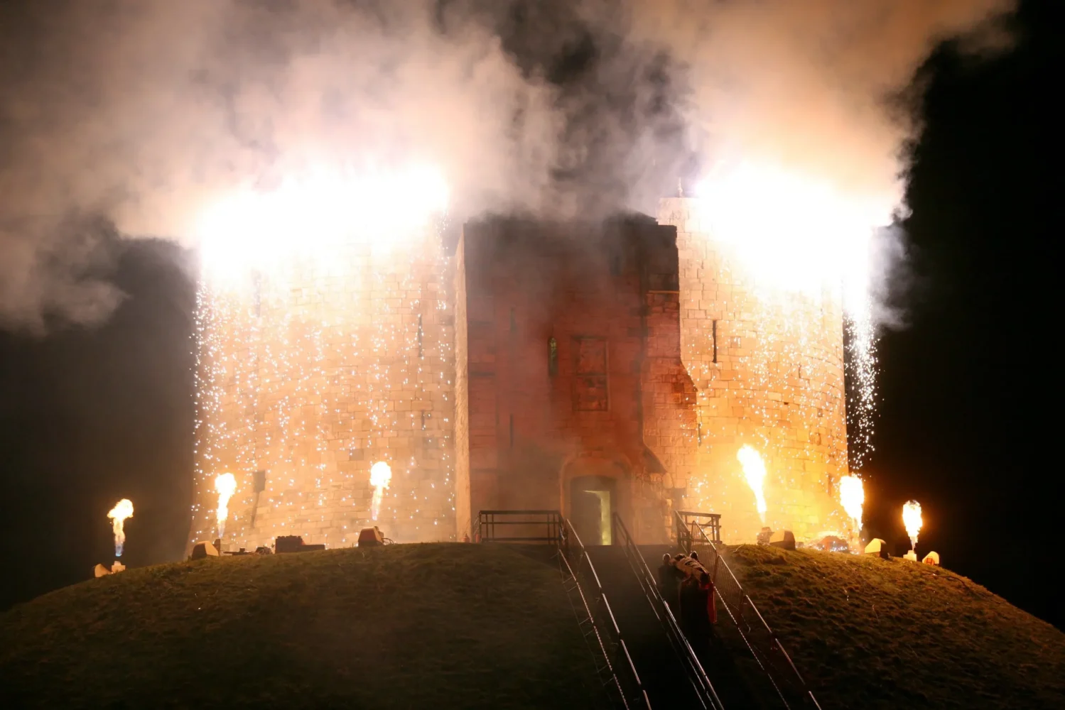 Clifford’s Tower illuminated by bright sparks and fire effects during the Festival Finale, with fire bursting from below.